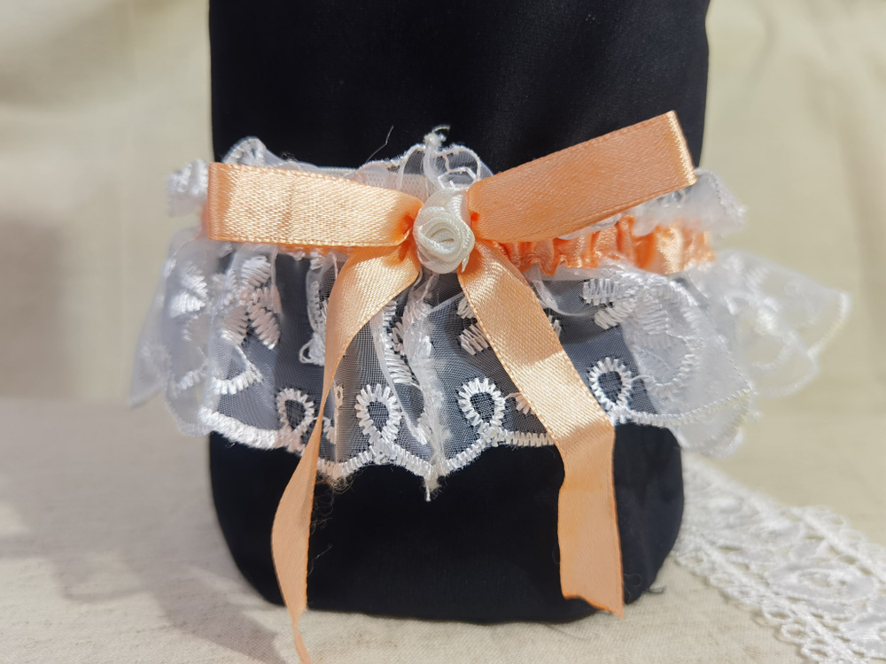 Подвязка для невесты кружевная в белом цвете с персиковым бантом.  #1