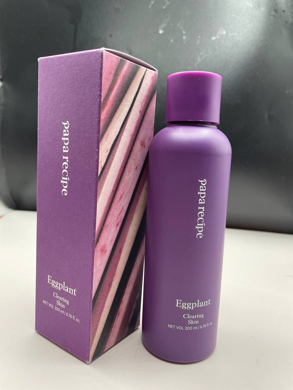 Успокаивающий тоник для кожи Eggplant Clearing Skin корейского бренда Papa recipe помогает контролировать общее состояние кожи, а также  превосходно увлажняет кожу. Тоник для лица содержит 87% экстракта плодов баклажанов, обладающий питательными веществами. Экстракт баклажана содержит много витаминов, минералов. 