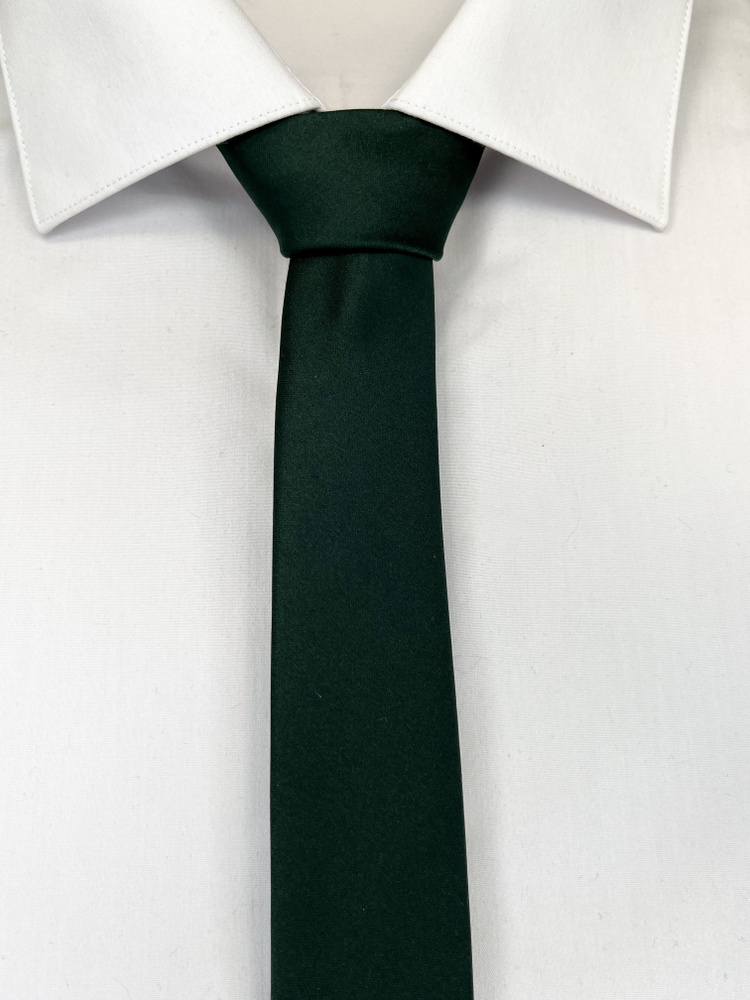 Узкий темно-зеленый галстук. Галстук селедка и белая рубашка. Галстук чуть выше ремня.